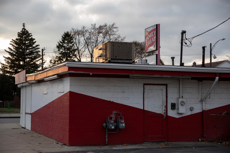 A white and red building with a sign at the top that reads "Family Treat" with the sun peaking through some clouds to the left.