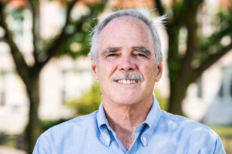 A portrait of a man in a light blue shirt.